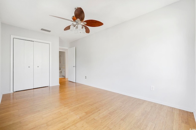 unfurnished bedroom featuring ceiling fan, visible vents, baseboards, light wood-style floors, and a closet