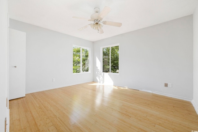 spare room featuring ceiling fan, light wood-style flooring, and baseboards