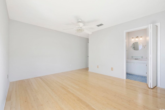 unfurnished bedroom featuring visible vents, ceiling fan, connected bathroom, a sink, and wood finished floors