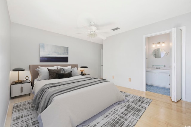 bedroom with ceiling fan, connected bathroom, a sink, visible vents, and light wood-style floors