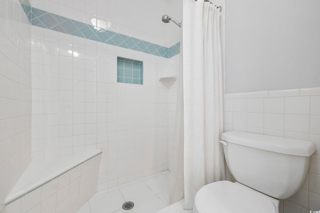 full bath with toilet, a wainscoted wall, tile walls, and tiled shower