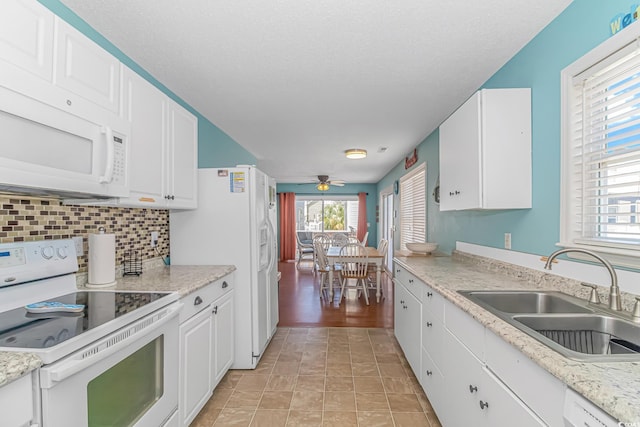 kitchen featuring white cabinetry, sink, backsplash, and white appliances