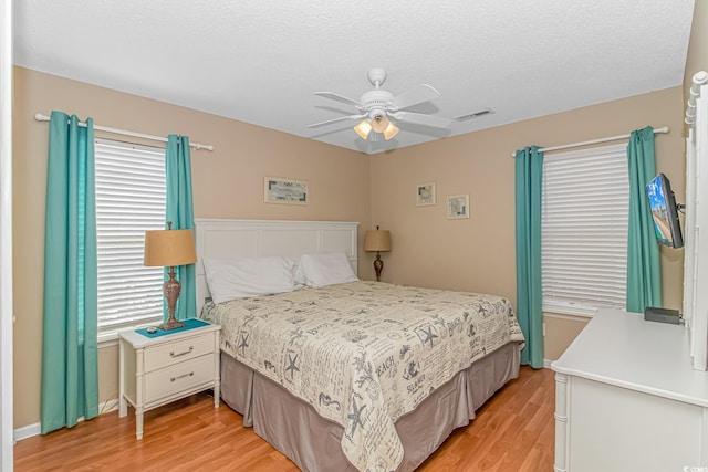 bedroom with multiple windows, light hardwood / wood-style floors, and ceiling fan