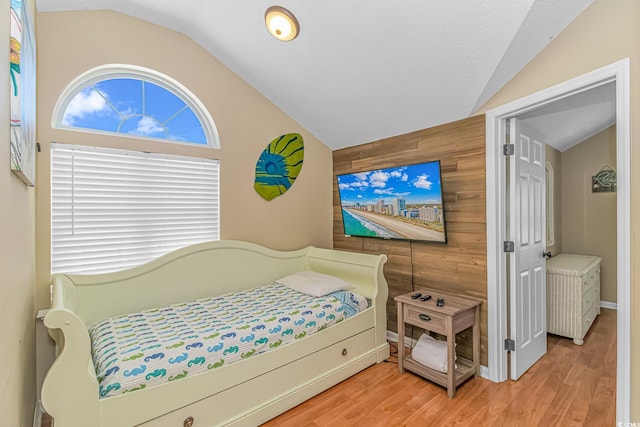 bedroom featuring vaulted ceiling, hardwood / wood-style floors, and wood walls