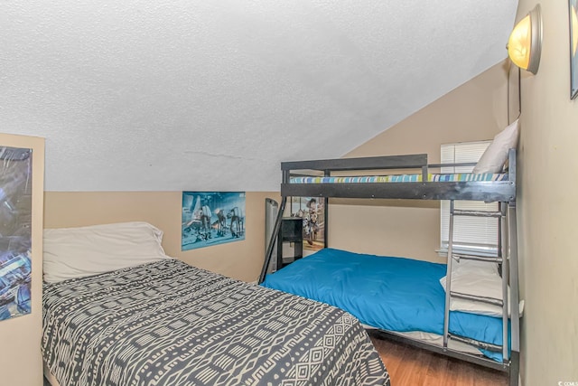 bedroom with hardwood / wood-style floors, vaulted ceiling, and a textured ceiling