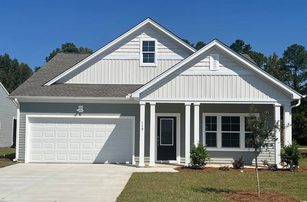 view of front of home featuring a garage, covered porch, and a front lawn