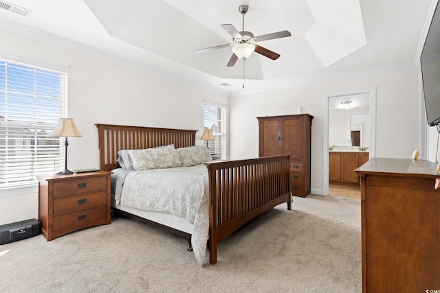 carpeted bedroom with ceiling fan, a raised ceiling, ornamental molding, and connected bathroom