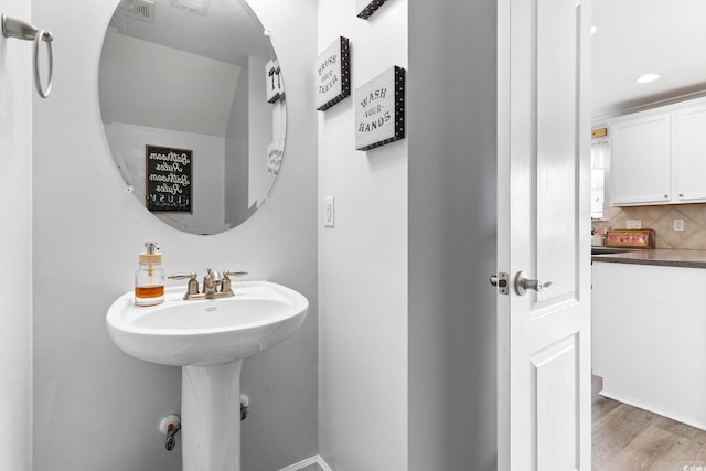 bathroom with hardwood / wood-style floors and tasteful backsplash