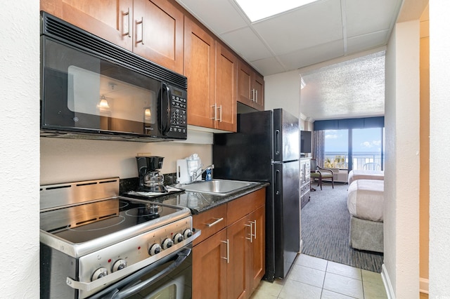 kitchen featuring a paneled ceiling, black appliances, sink, light tile patterned floors, and a textured ceiling