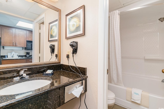 full bathroom with shower / bath combination with curtain, a drop ceiling, toilet, and vanity