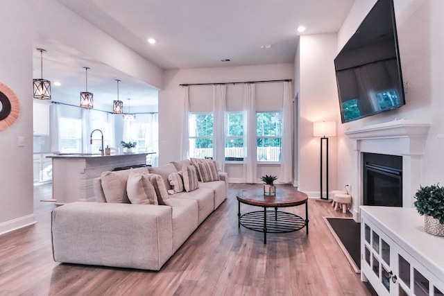 living room with sink, an inviting chandelier, a wealth of natural light, and hardwood / wood-style flooring