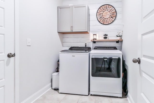 laundry room with light tile patterned flooring, washing machine and dryer, and cabinets