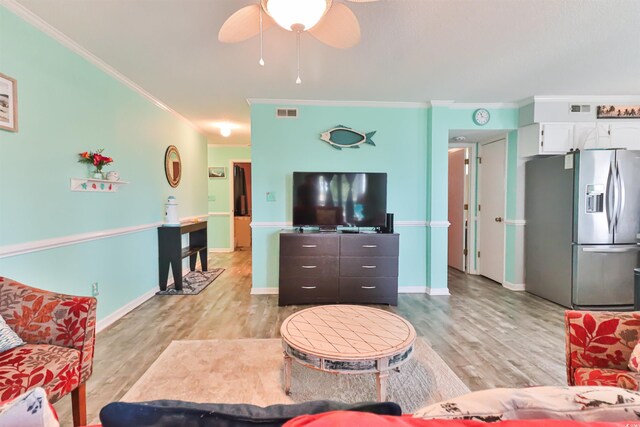 living room featuring ornamental molding, light wood-type flooring, and ceiling fan