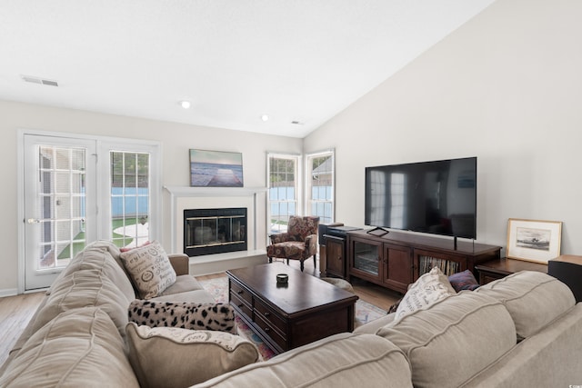 living room with light wood-type flooring and high vaulted ceiling