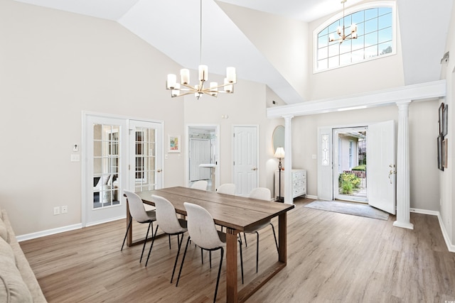 dining area featuring high vaulted ceiling, light hardwood / wood-style floors, a chandelier, and decorative columns