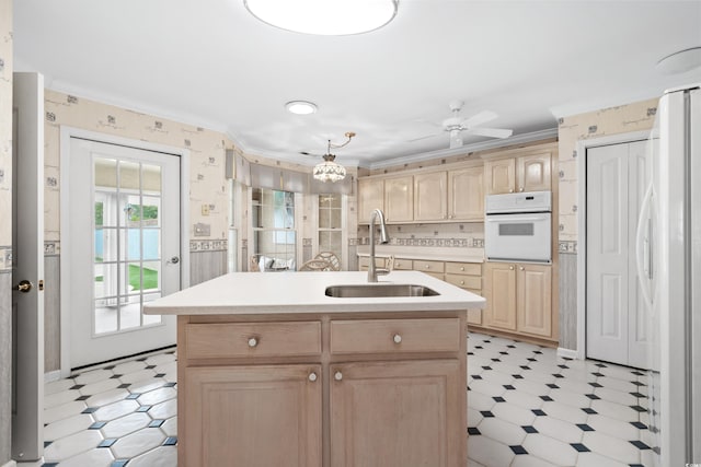 kitchen with sink, decorative backsplash, white appliances, light brown cabinetry, and an island with sink