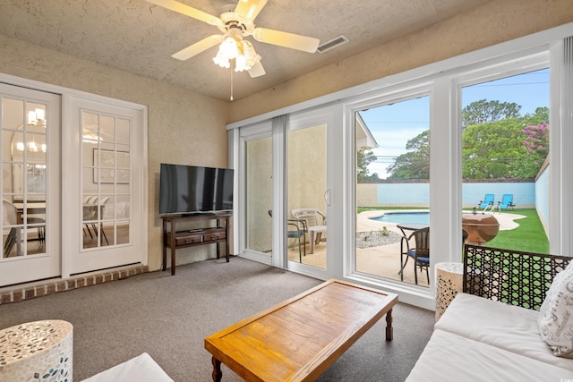 carpeted living room with ceiling fan and a textured ceiling