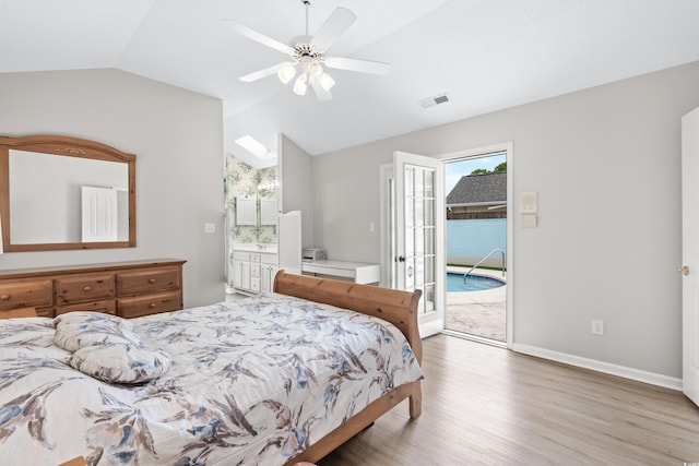 bedroom featuring vaulted ceiling, access to exterior, ensuite bath, ceiling fan, and hardwood / wood-style flooring