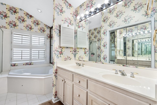 bathroom featuring lofted ceiling, a tub to relax in, double sink vanity, and tile patterned floors