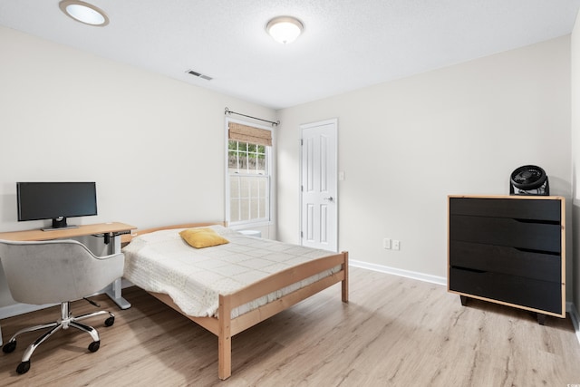 bedroom featuring light wood-style flooring, visible vents, and baseboards