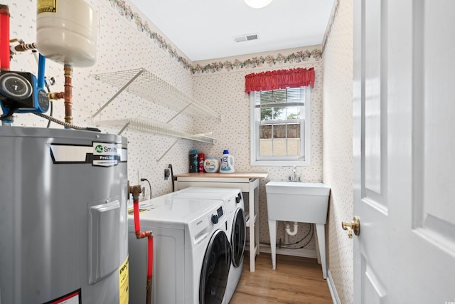 clothes washing area with independent washer and dryer, electric water heater, and wood-type flooring