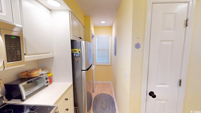 kitchen featuring tile patterned flooring, appliances with stainless steel finishes, and white cabinets