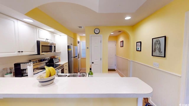 kitchen with white cabinets, kitchen peninsula, and stainless steel appliances