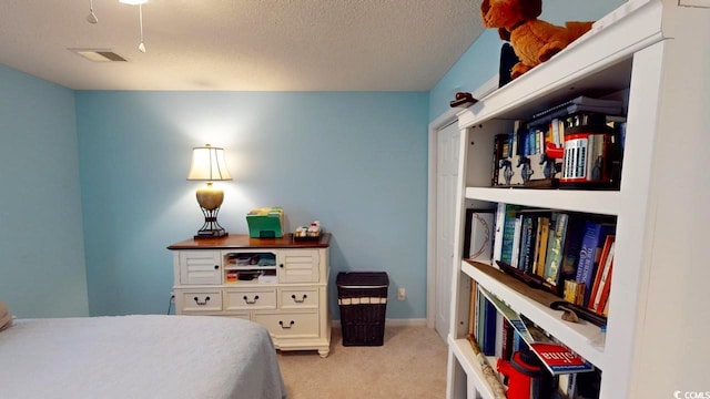 bedroom with light colored carpet and a textured ceiling