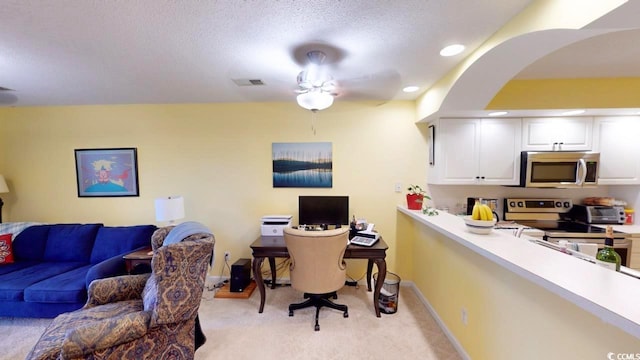 office space with a textured ceiling, light colored carpet, and ceiling fan