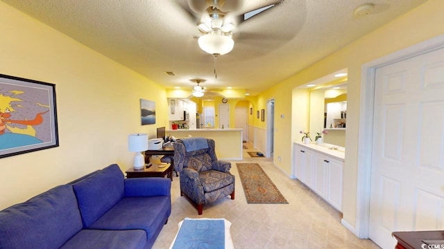 living room featuring a textured ceiling, ceiling fan, and light carpet