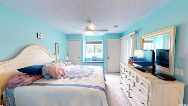 bedroom with multiple windows, ceiling fan, light carpet, and a textured ceiling