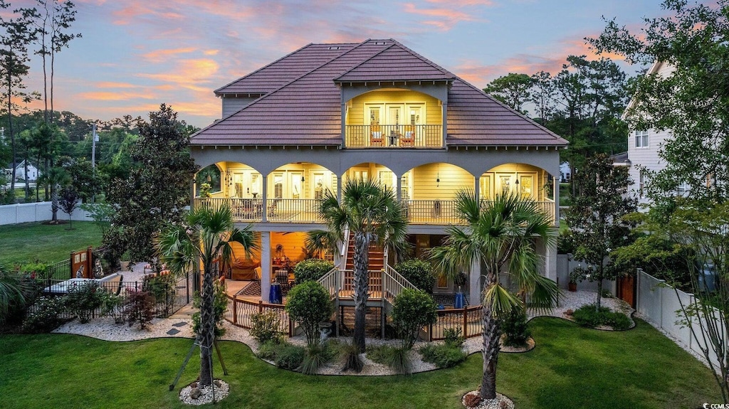 view of front of home featuring a balcony and a yard