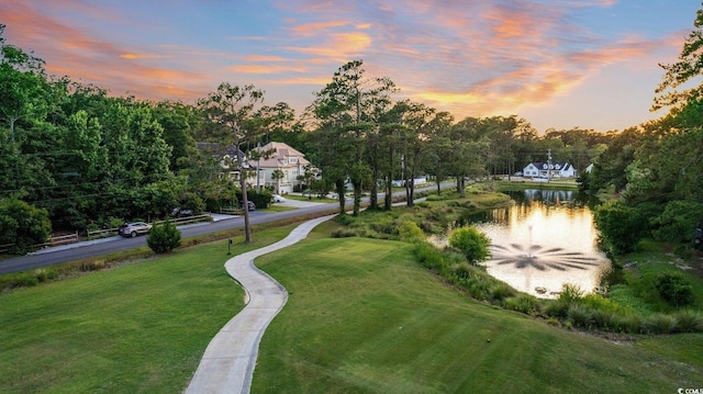 view of home's community with a water view and a lawn