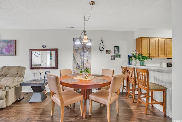 dining area featuring dark hardwood / wood-style flooring, a textured ceiling, and an inviting chandelier