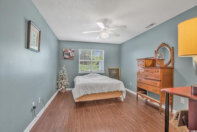 bedroom featuring ceiling fan, hardwood / wood-style floors, and a textured ceiling