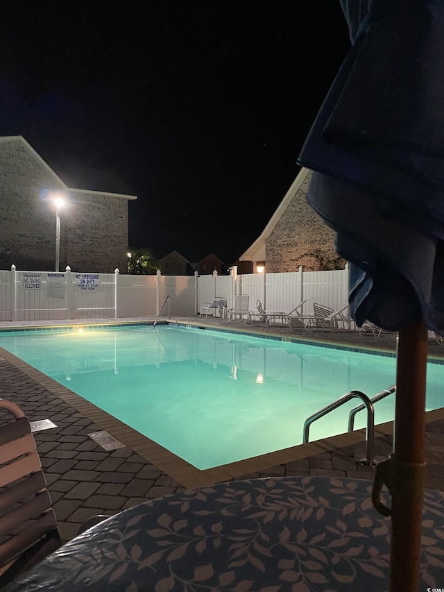 view of pool at twilight