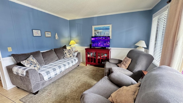 living room featuring tile patterned flooring, ornamental molding, a textured ceiling, and wainscoting