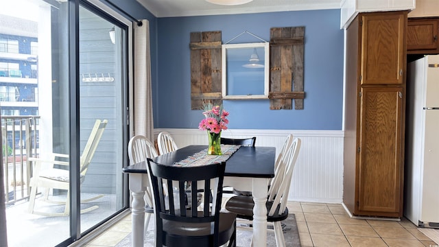 dining room featuring a wainscoted wall, light tile patterned floors, and plenty of natural light