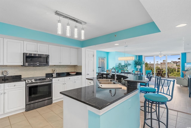 kitchen featuring stainless steel appliances, sink, an island with sink, white cabinets, and a kitchen breakfast bar