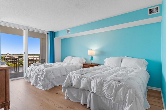 bedroom featuring access to outside, light hardwood / wood-style flooring, and a textured ceiling