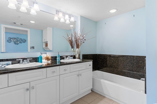 bathroom featuring a washtub, double sink vanity, a textured ceiling, and tile patterned floors