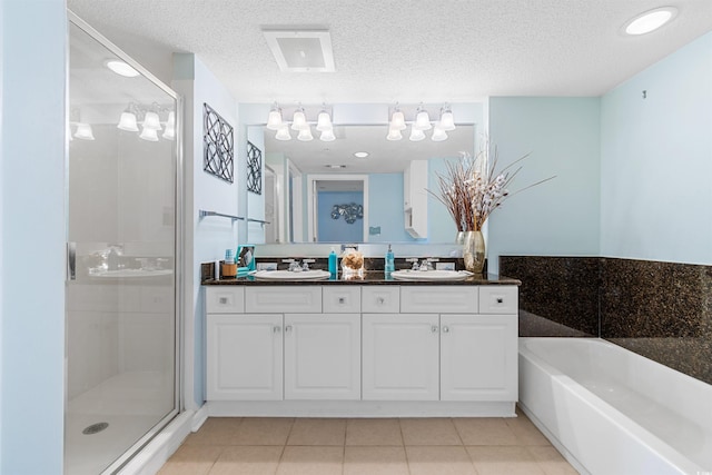 bathroom with dual vanity, separate shower and tub, a textured ceiling, and tile patterned flooring