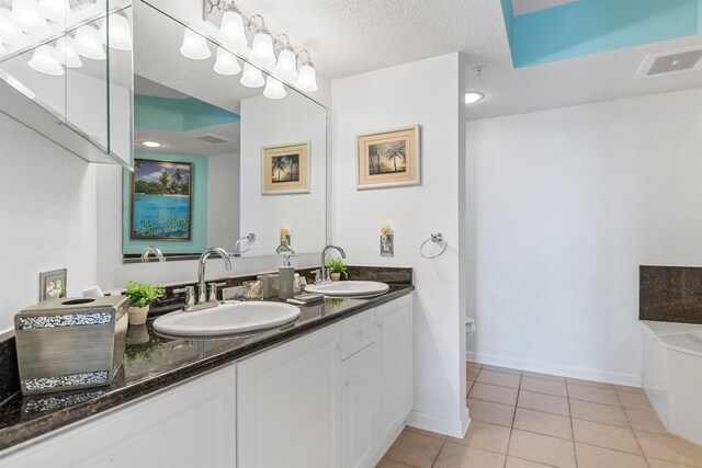 bathroom featuring a tub to relax in, a textured ceiling, dual vanity, and tile patterned floors