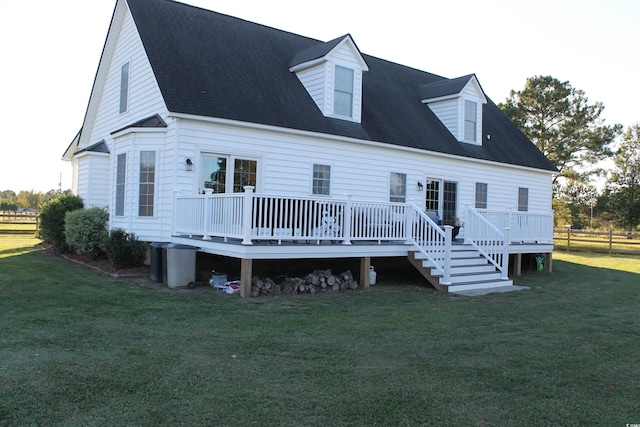 rear view of house featuring a wooden deck and a lawn