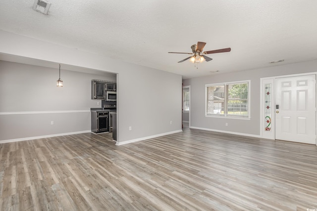 unfurnished living room with ceiling fan, a textured ceiling, and light hardwood / wood-style floors