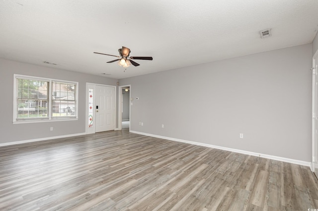 unfurnished room with ceiling fan, a textured ceiling, and light wood-type flooring