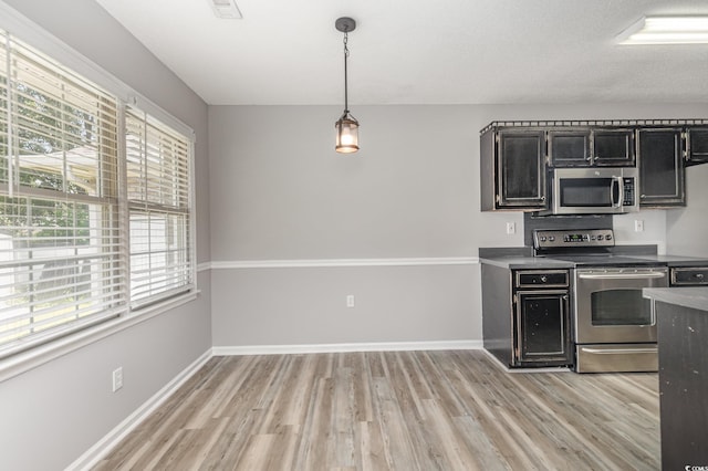 kitchen with decorative light fixtures, light wood-type flooring, and appliances with stainless steel finishes