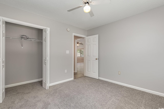 unfurnished bedroom with ceiling fan, light colored carpet, a textured ceiling, and a closet