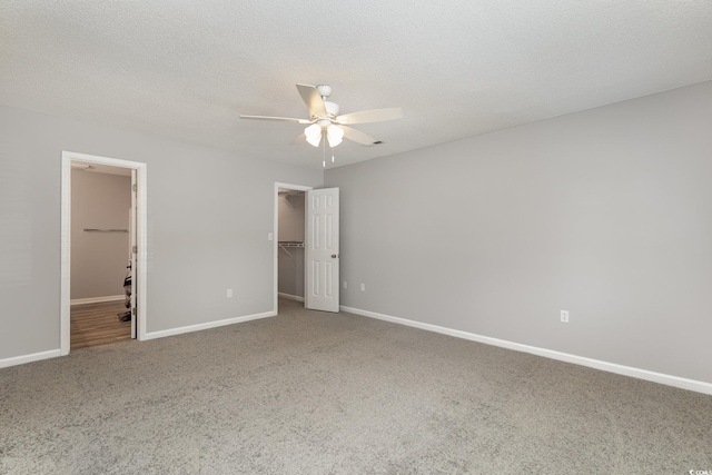 unfurnished bedroom with ceiling fan, carpet, a textured ceiling, a walk in closet, and a closet