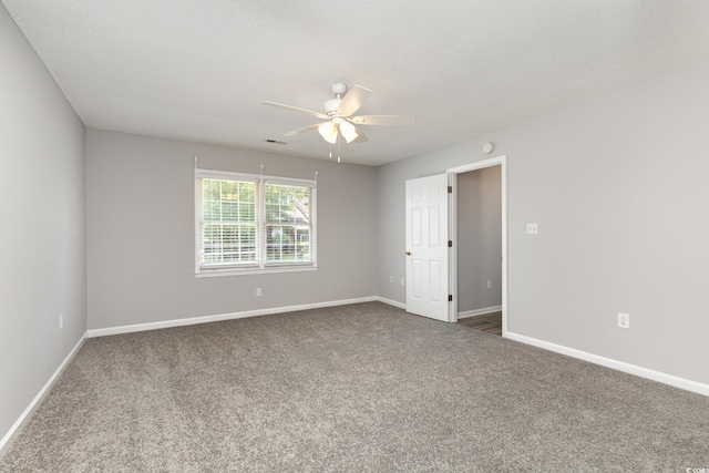 empty room featuring ceiling fan, a textured ceiling, and dark carpet